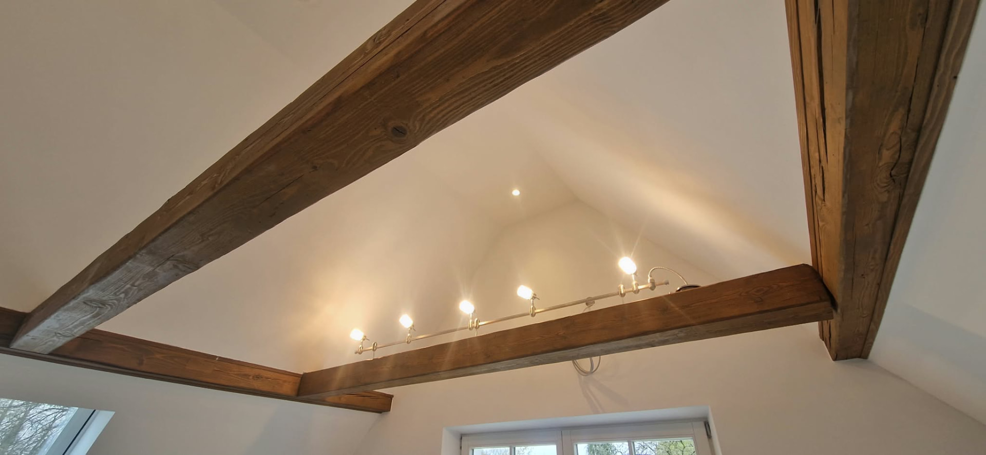 Leuchten entlang eines Holzbalkens und Deckenspots