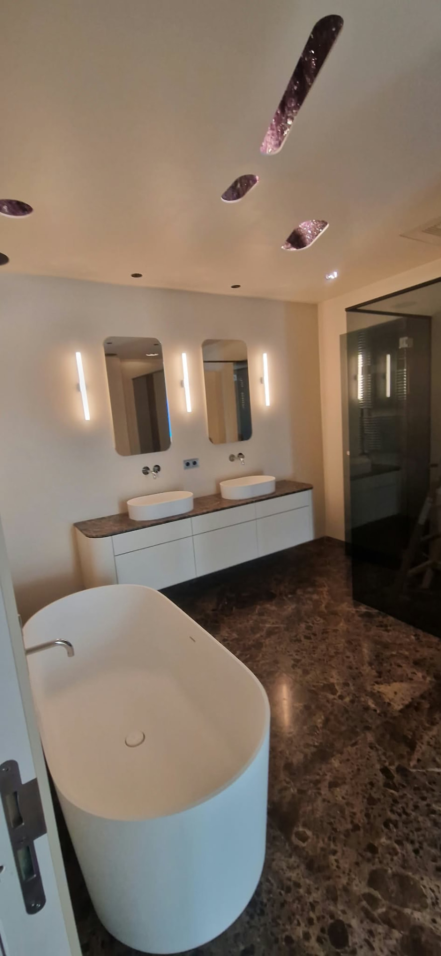 Badezimmer mit beleuchteten Spiegeln und Wandlampen